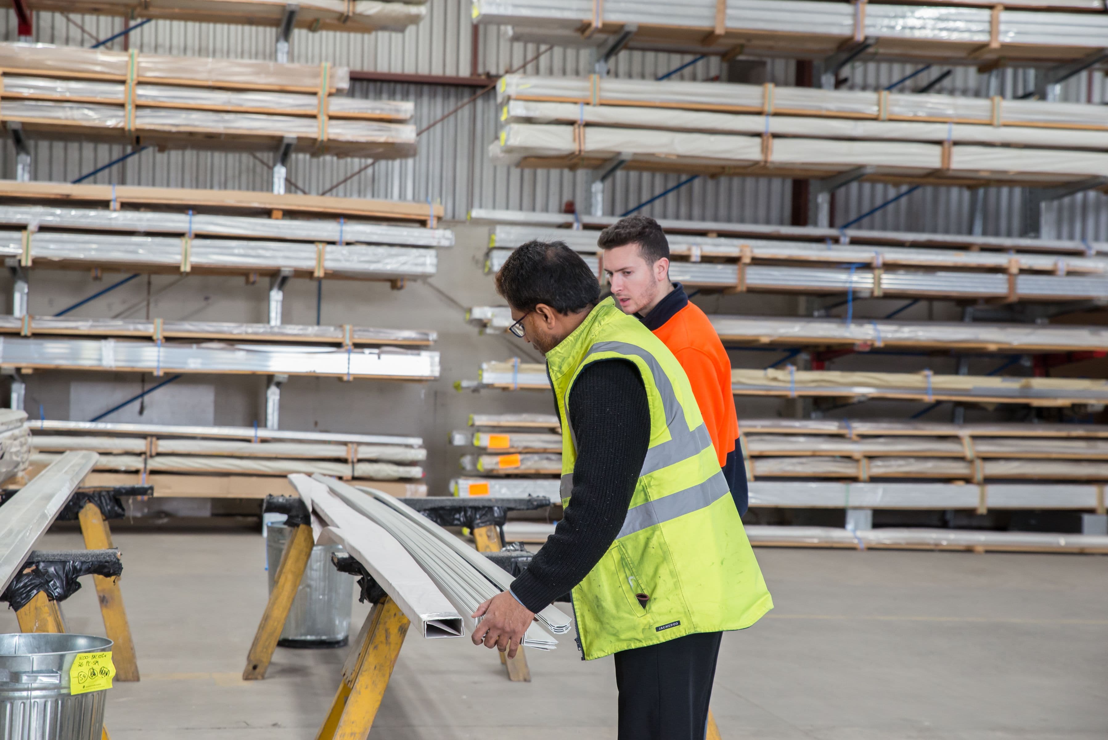 Two workers inspecting construction materials inside a warehouse