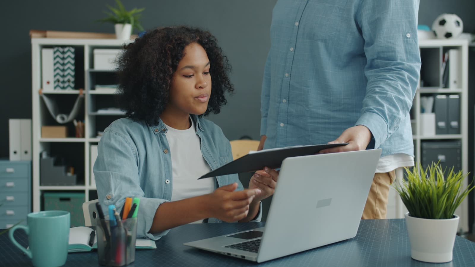 Two colleagues reviewing supplier documents beside a laptop