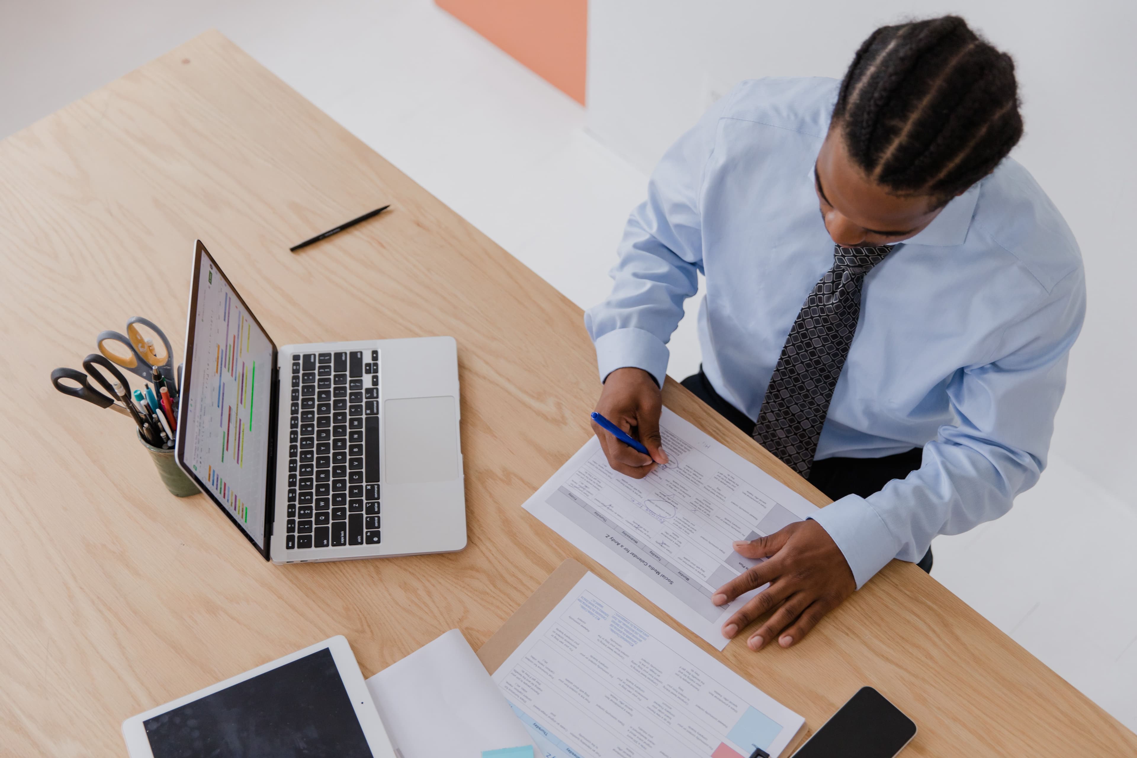 A business professional reviewing and signing supplier documents at an office desk